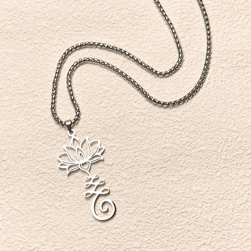 Loose silver chain with lotus pendant flat lay on neutral beige wall background showing pendant design detail