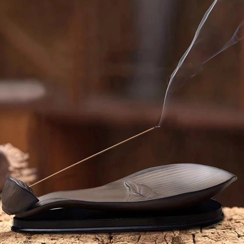Burning incense stick in lotus pod ceramic burner with aromatic smoke rising, matte brown finish with lotus relief
