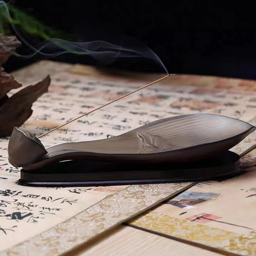 Front view of lotus pod ceramic incense burner with visible incense smoke and embossed lotus relief on dark ceramic base