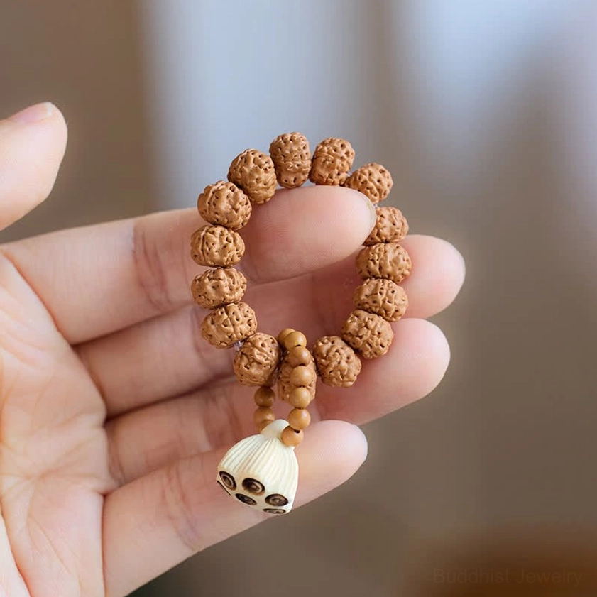 Side view of Buddhist charm meditation bracelet with dangling lotus pod pendant and textured wood beads held in open palm