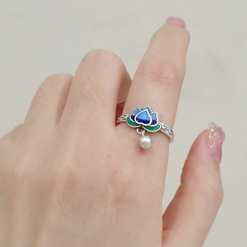 Handcrafted Buddhist lotus ring showing intricate enamel work with blue petals, silver bell accent, and engraved silver band