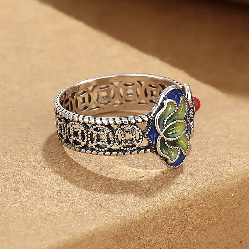 Side perspective of adjustable lotus ruyi ring demonstrating braided edge and hollow coin band texture