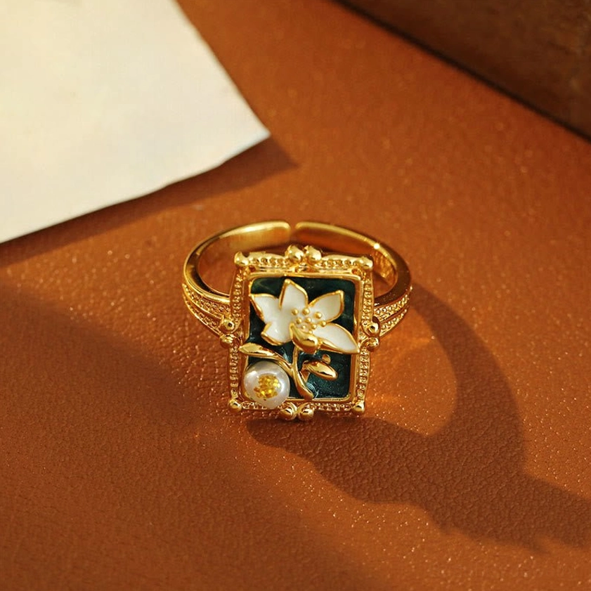 Side view of adjustable lotus pearl ring - dark tray display showing ring band profile and mounted ornament