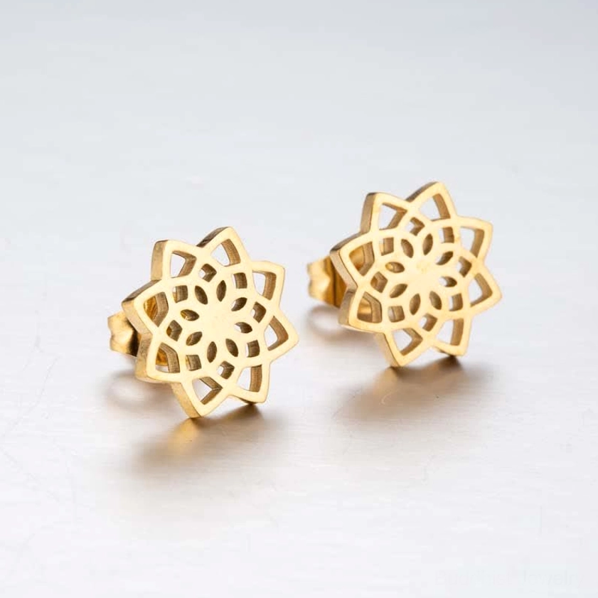 Gold tone lotus stud earrings in flat lay showing symmetrical cutout flower design and warm finish