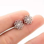 Silver lotus stud earrings held in fingertips showing 11mm diameter size and hollow floral cutout design