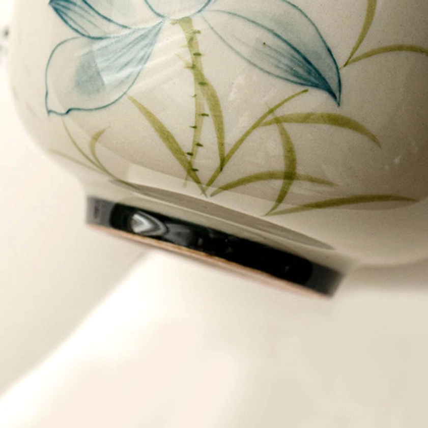 Close-up of ceramic tea cup bottom with black glazed rim and side lotus pattern detail - Buddhist mindfulness cup