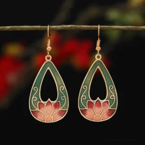 Teardrop lotus enamel drop earrings in green and red with gold metal trim, hanging on twig with floral background