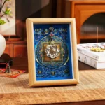 Sacred lotus thangka photo frame with blue mandala background in light wood finish displayed on Chinese-style tea table