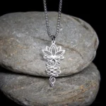 Lotus unalome chakra stainless steel Buddhist necklace pendant overhead close-up view on stone backdrop