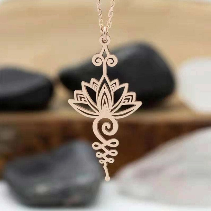 Close-up view of light metallic lotus unalome necklace showing fine hollow carved details and spiritual symbolism on wooden surface