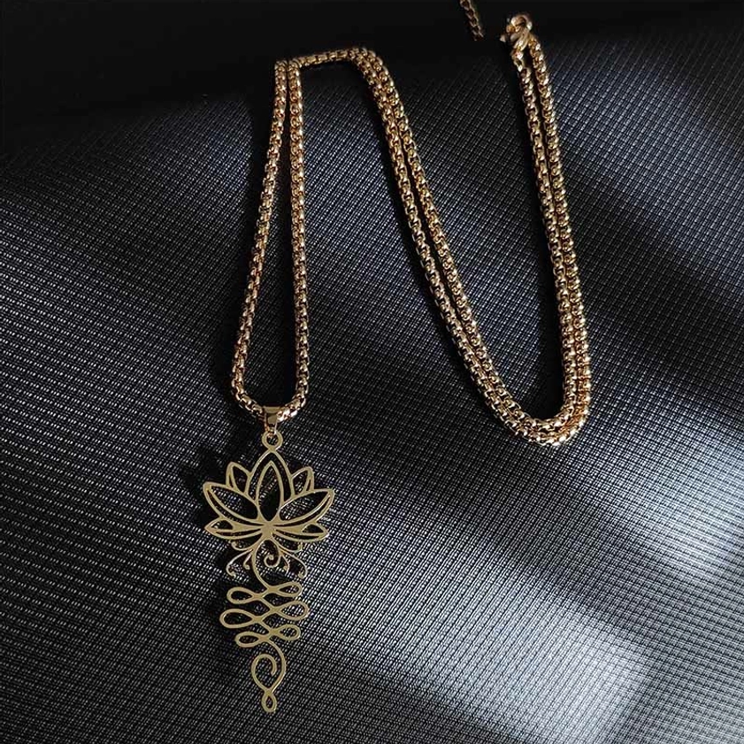Gold tone lotus unalome Buddhist necklace pendant twisted box chain oblique view dark background