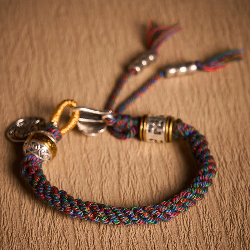Braided Buddhist Bracelet with Magnetic Clasp and Vintage Silver Metal Details on Wooden Table