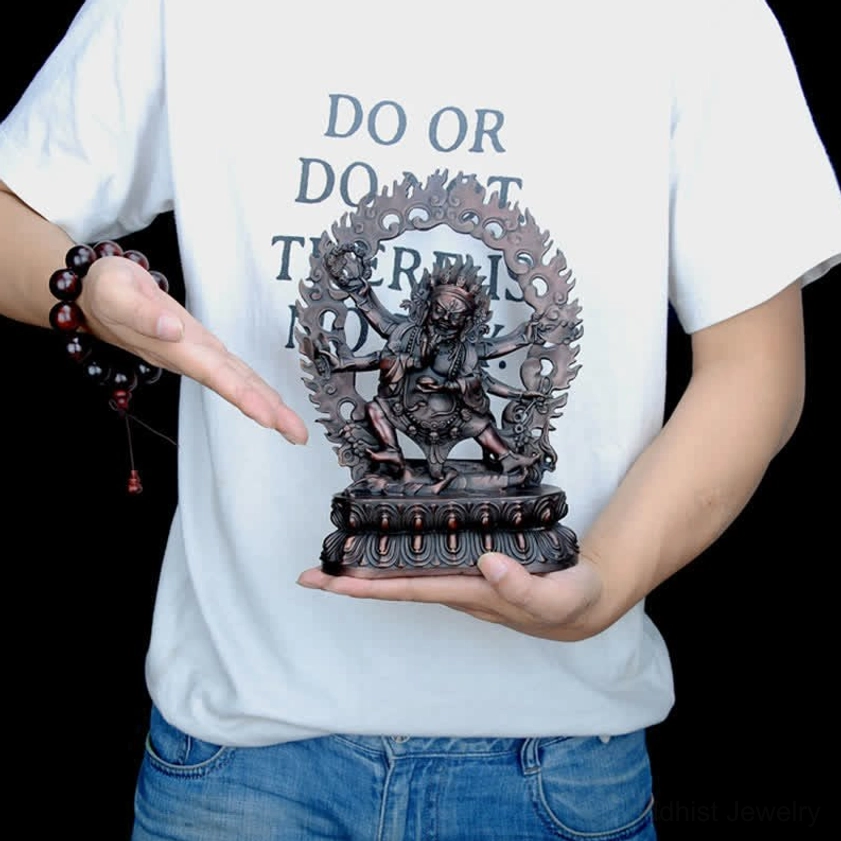Hand holding small Mahakala six-armed copper statue showing size and portable scale for personal altar or meditation space