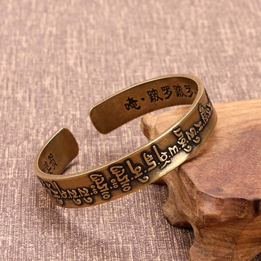 Mahapratisara Sanskrit mantra brass open cuff bracelet on wooden stand with linen fabric background showing engraved mantras