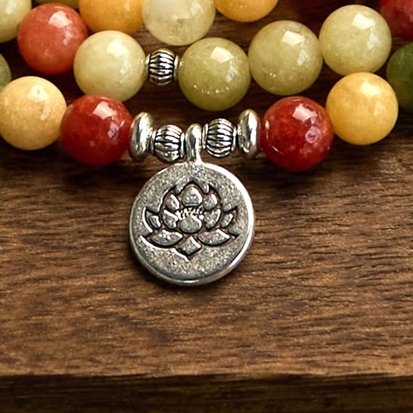 Macro view of 108 mala prayer beads with large engraved lotus silver pendant and decorative metal bead spacers on wooden surface