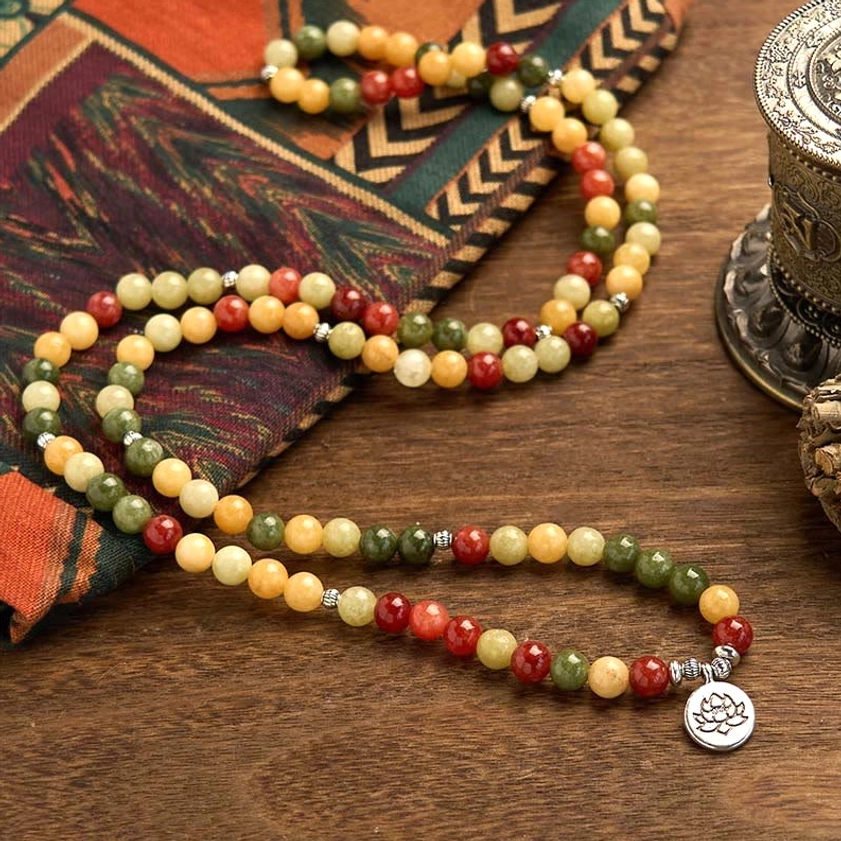 Close-up view of 108 mala beads showing round natural stone beads in topaz red jasper and green jasper with lotus silver charm