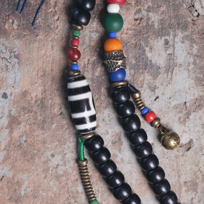 Mala bead component close-up showing dzi bead, colorful beads, and brass metal details