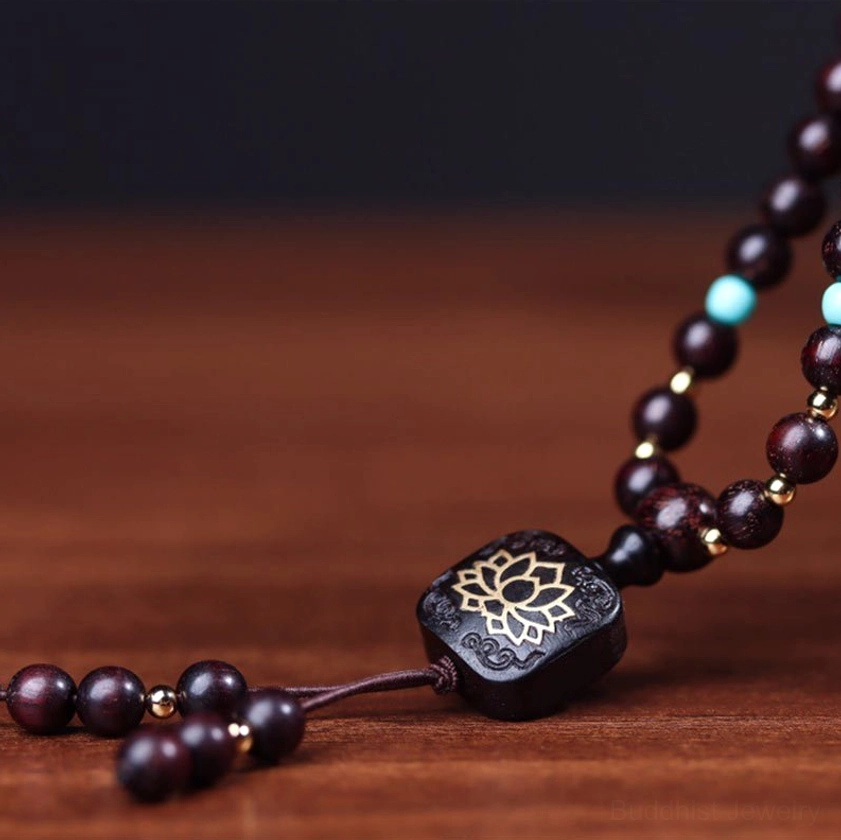 Flat-lay sandalwood mala set showing hand-engraved lotus pendant with turquoise and gold spacer beads