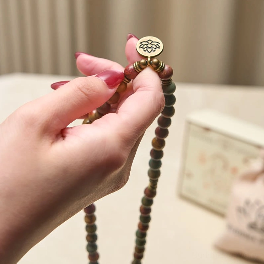 Handcrafted mala beads held in hand showing gemstone texture and lotus accent