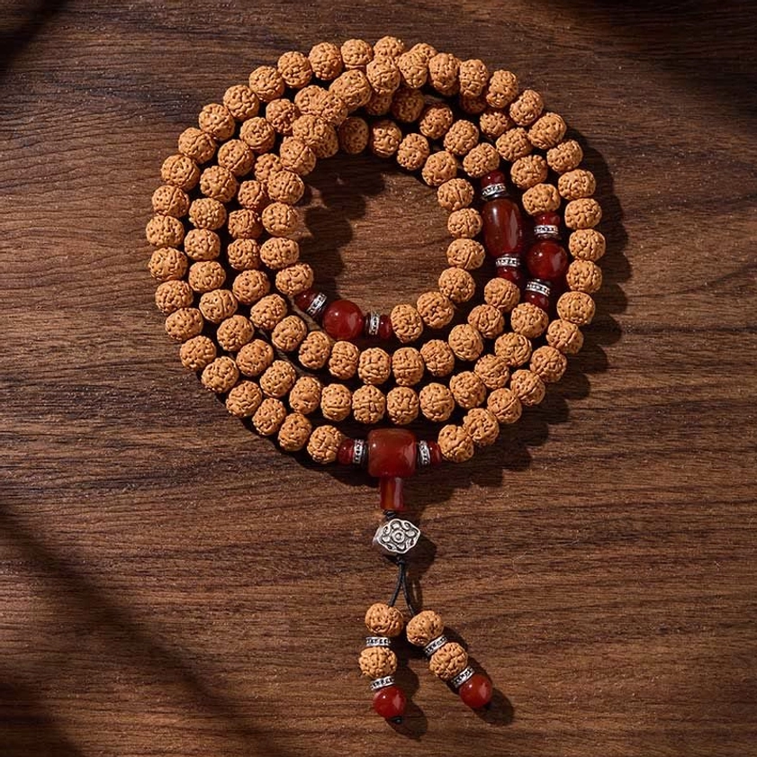 Overhead view of Buddhist prayer mala with light brown bodhi beads red agate and silver spacers wooden background