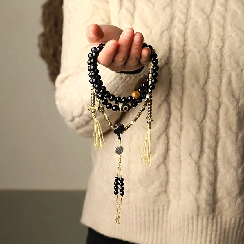 Wearable mala beads bracelet in hand showing black onyx and dzi bead details with elastic band fit