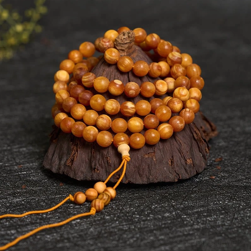 Stacked resin-rich pine wood beads with guru bead and tassel on wooden display stand, close-up view