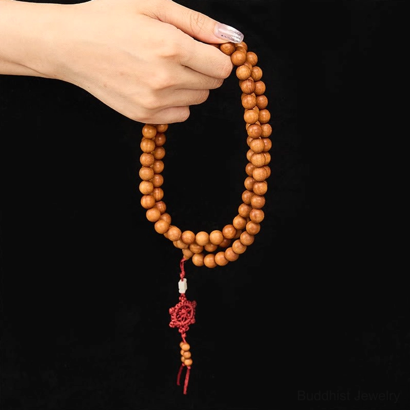 Red sandalwood Buddhist mala on wrist showing how to wear prayer beads for daily mindfulness