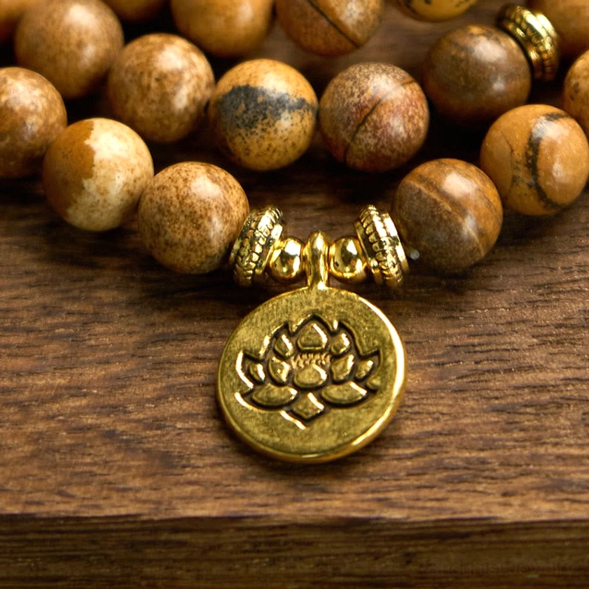 Picture jasper 108 bead mala bracelet with gold lotus charm and spacer beads on wooden table