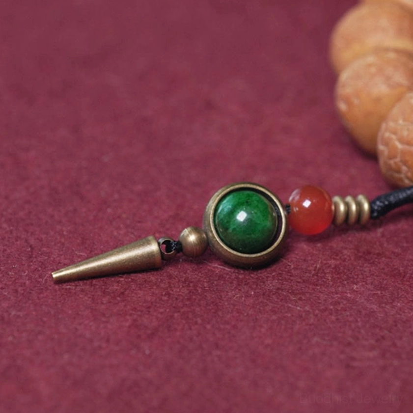 Buddhist mala bracelet with green bead, red agate, and brass tassel pendant components