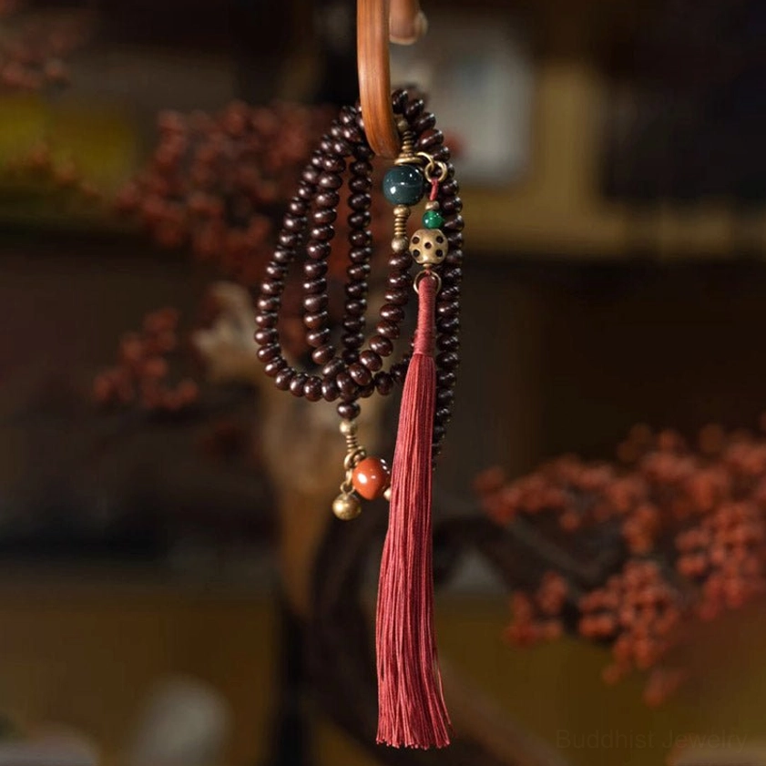 Hanging 108 Bodhi Seed Mala Prayer Bracelet showing full length red tassel and mixed metal stone accents