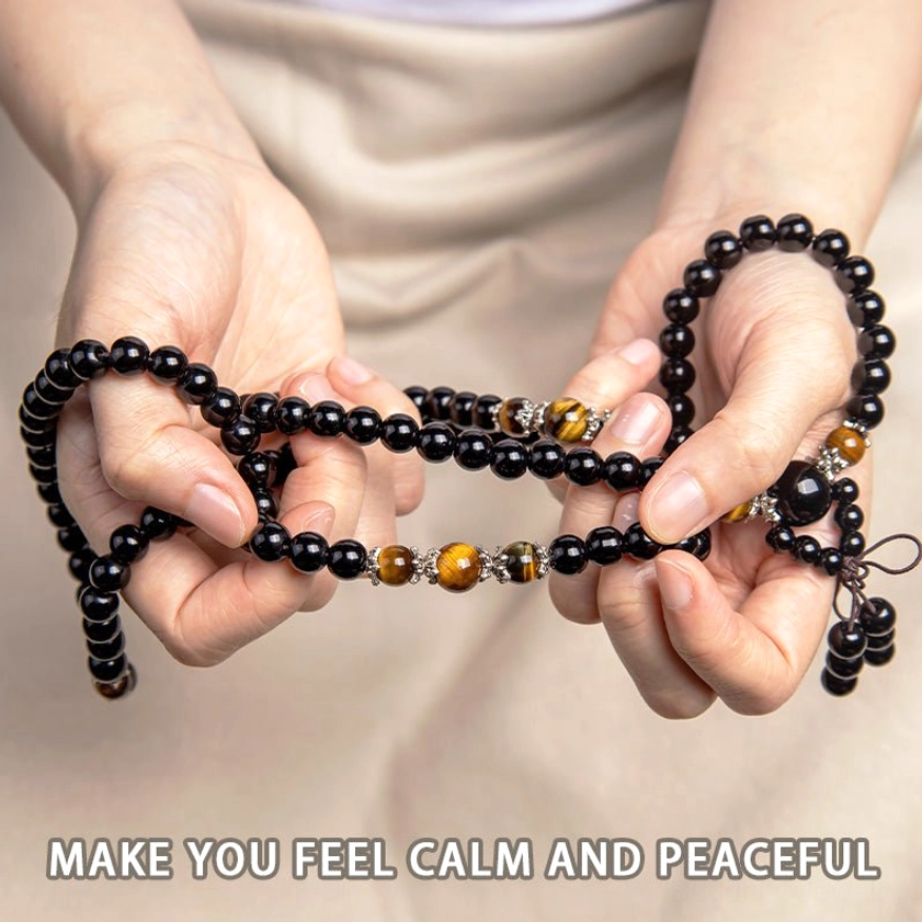 Hand holding 108 bead black obsidian tiger eye prayer mala bracelet with slogan 'make you feel calm and peaceful'