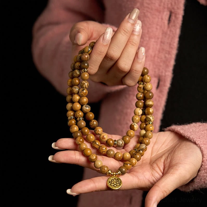 Picture jasper mala bracelet held in hands showing full 108 bead strand with lotus charm