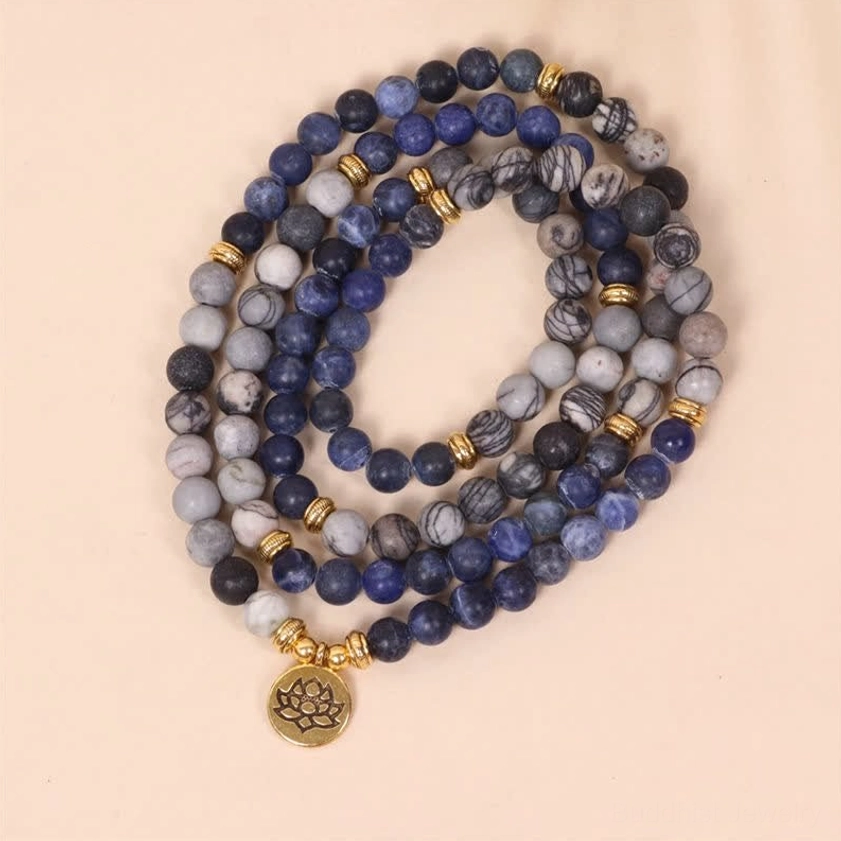 Buddhist mala beads featuring blue sodalite and striped zebra jasper stones with gold spacers and lotus pendant