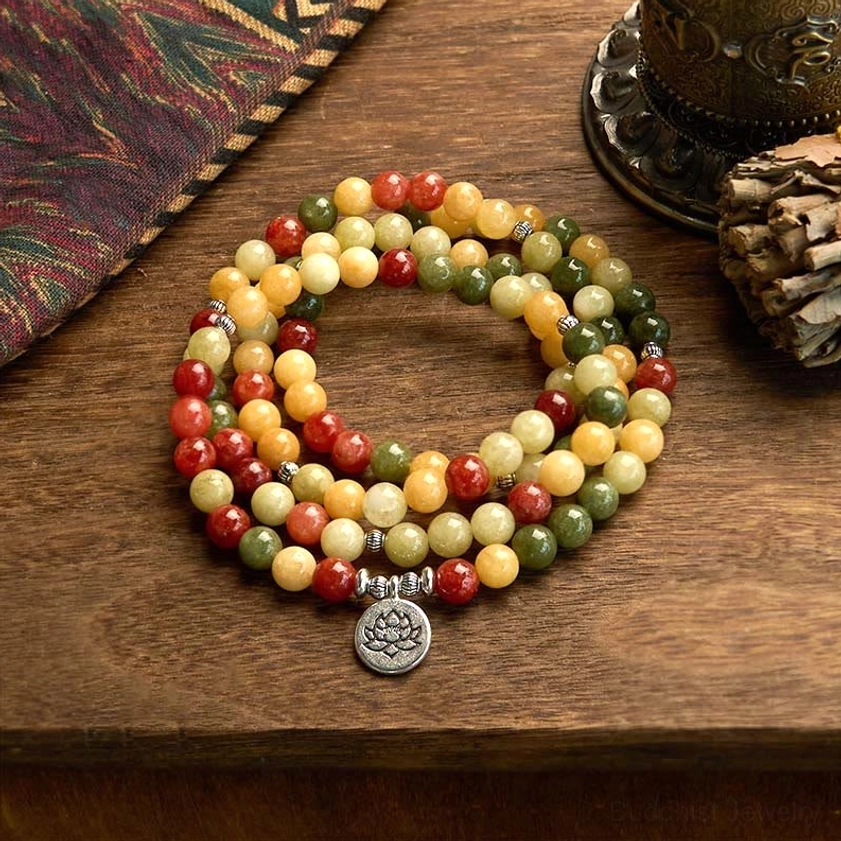 108 mala bead bracelet with topaz red jasper green jasper and lotus charm pendant displayed on wooden table with ethnic decor