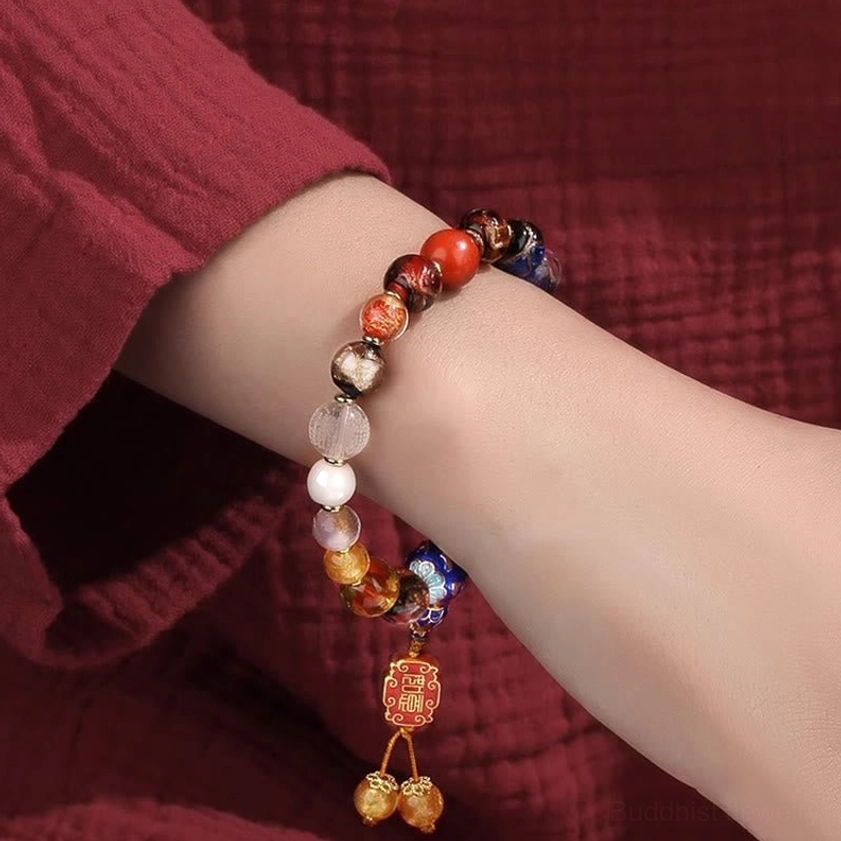 Worn incense ash liuli glass mala bracelet on human wrist showing multi-color beaded design with enamel pendant and golden bells