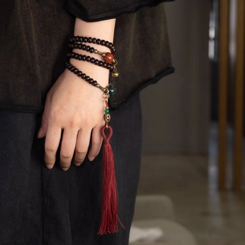 Wrist-worn 108 Mala Prayer Bracelet close-up showing multi-strand wrap, red tassel, and decorative metal charms