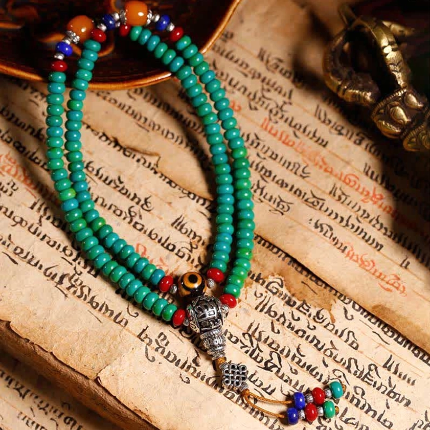 Unfurled Buddhist prayer mala bracelet with turquoise beads and hand-painted dzi on vintage scripture background