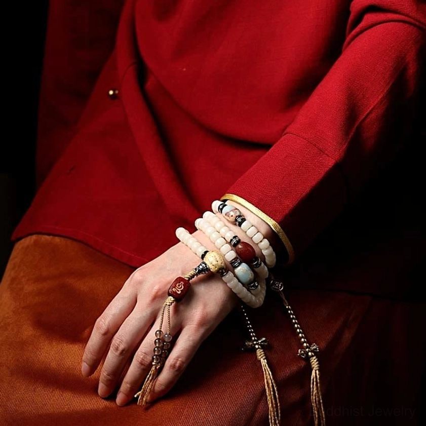 Tibetan prayer mala worn on wrist and body in traditional clothing, multiple layered malas with red agate and silver cross charms