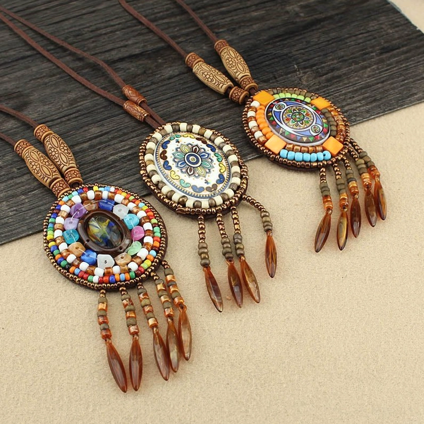 Two Buddhist mandala pendant necklaces with intricate beadwork and wooden carved accents on dark wood surface