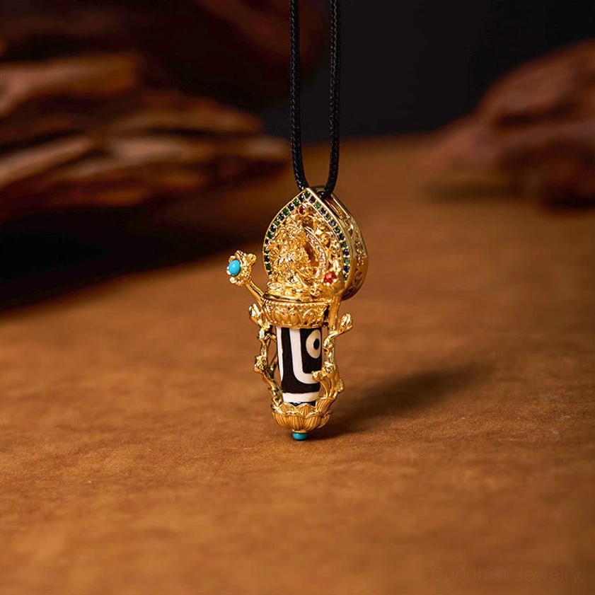 Manjusri Bodhisattva Dzi Bead Pendant Necklace with hand-painted two-eye dzi bead and gilded copper setting, front three-quarter view on wooden studio background