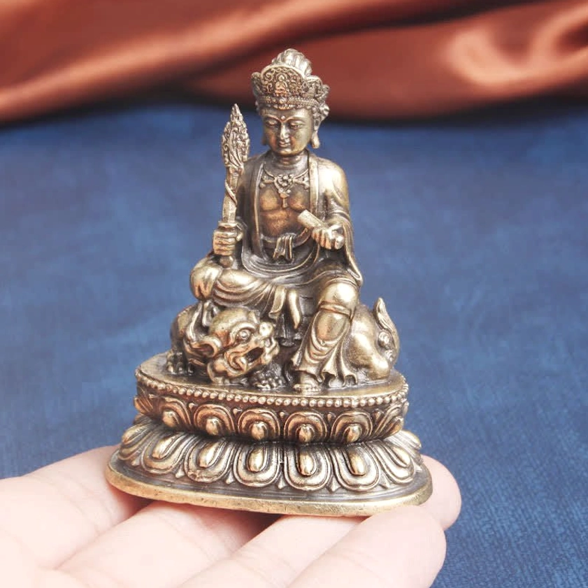 Pocket-sized Manjusri Bodhisattva statue held in palm demonstrating portable compact scale, bronze patina coloring, and seated position on Foo Lion lotus pedestal - portable meditation statue