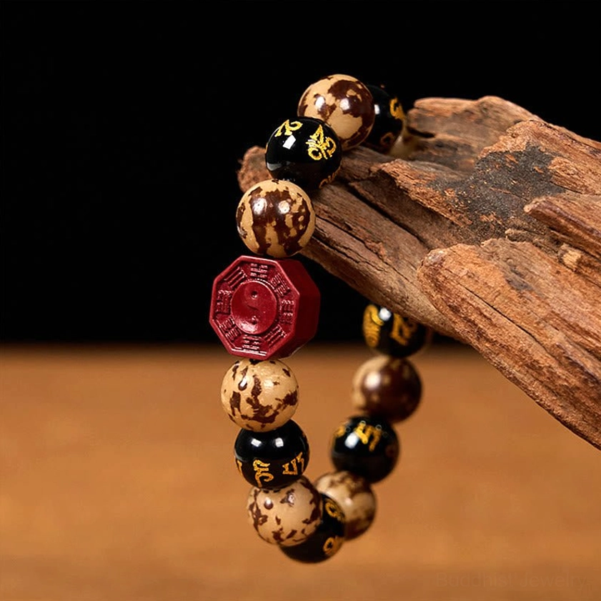 Om Mani Padme Hum mantra beaded bracelet low angle view with red cinnabar pendant and spotted Bodhi beads on wood prop