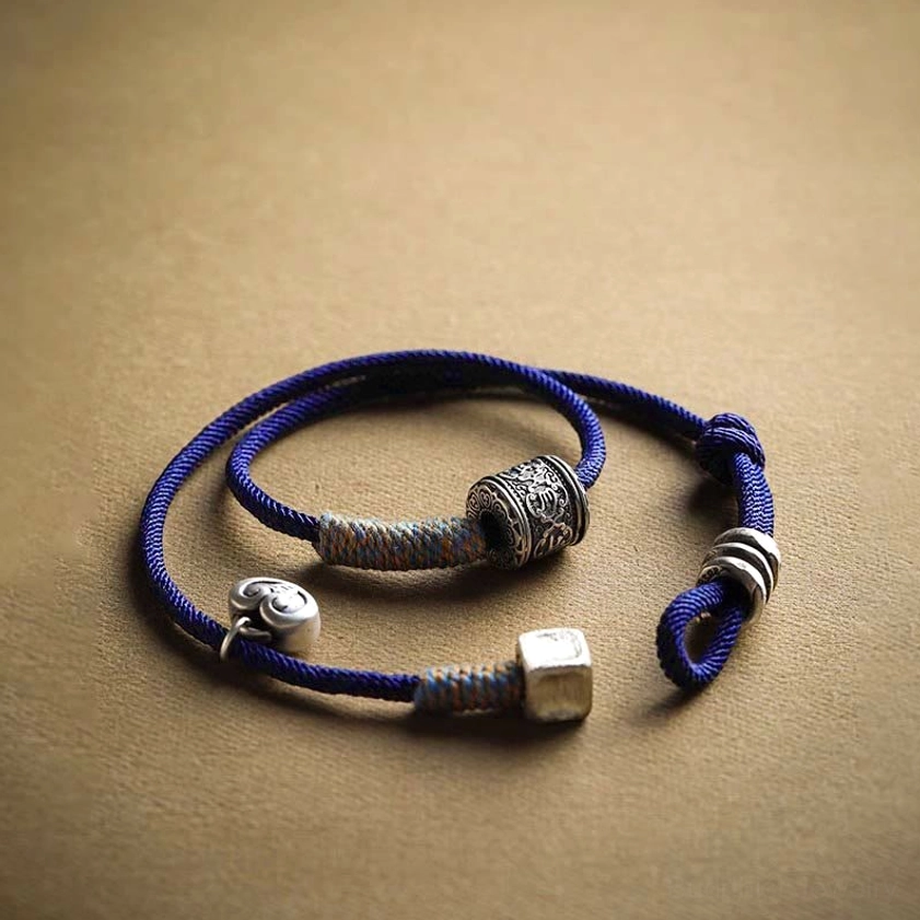 Handcrafted mantra bracelet detail showing engraved silver barrel bead and spiral adjustable closure