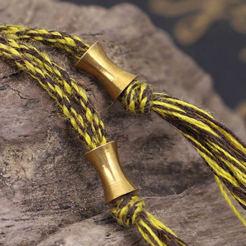 Macro detail of bracelet tassel and bronze metal fastener components on rough stone background
