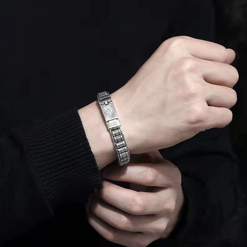 Buddhist copper bracelet worn on wrist with black knit clothing, close-up showing vintage silver finish and engraved mantra details
