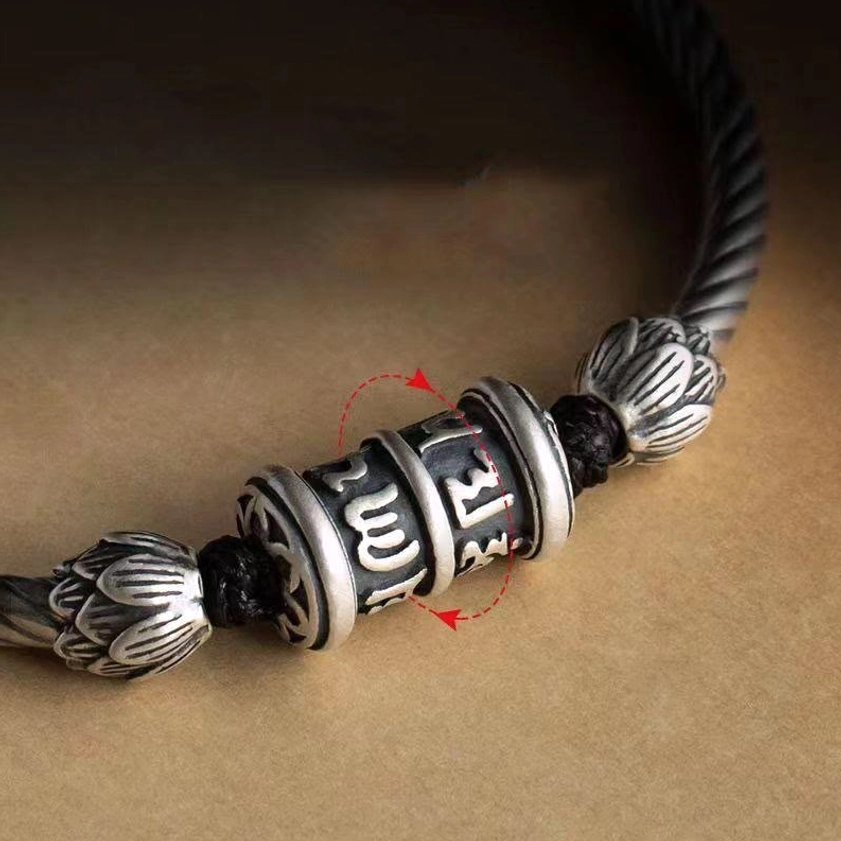 Close-up macro view of rotatable mantra cylinder with carved Sanskrit scriptures on om-mani-padme-hum spiritual bracelet