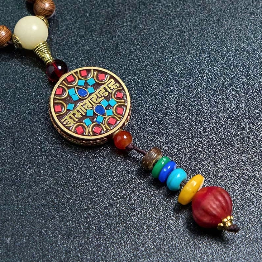 Macro photography of colorful mantra charm pendant with vibrant inlay details on Buddhist necklace