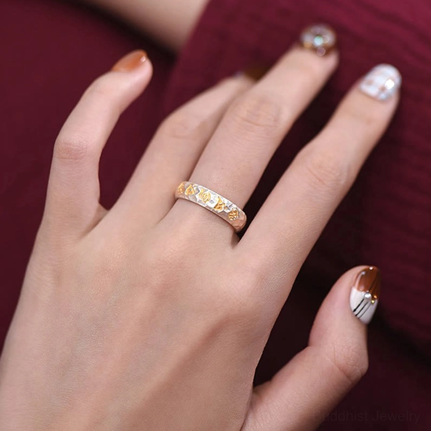 Mantra ring artistic photography highlighting two-tone metal contrast and gold Sanskrit letter prominence