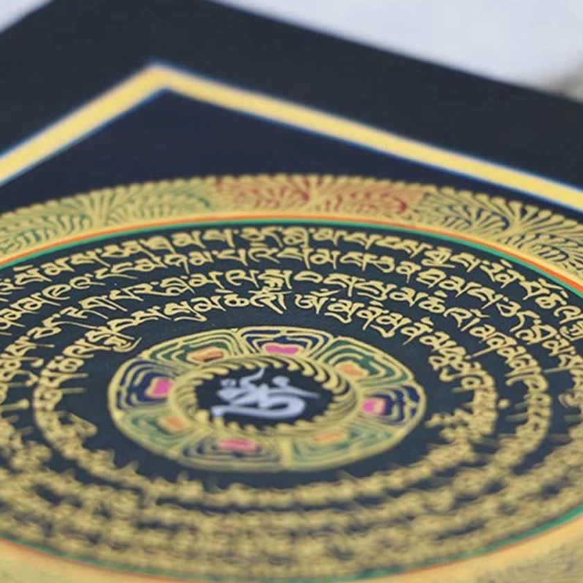 Extreme close-up detail of hand-painted mantra thangka showing intricate gold Sanskrit script and central Tibetan syllable motif – sacred Buddhist art detail