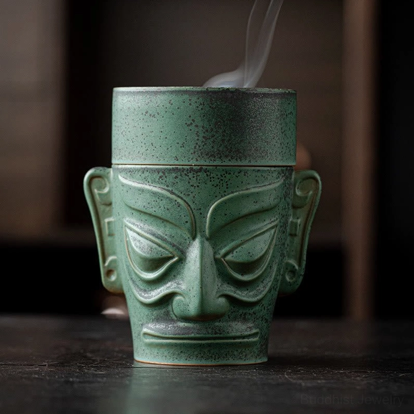 Front view of ceramic incense burner with sealed lid and faint drifting smoke, speckled green ceramic texture on dark wooden surface